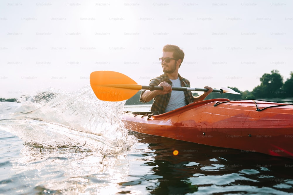 Handsome young man kayaking on lake and smiling