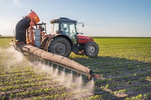 tractor spraying pesticides on soy bean