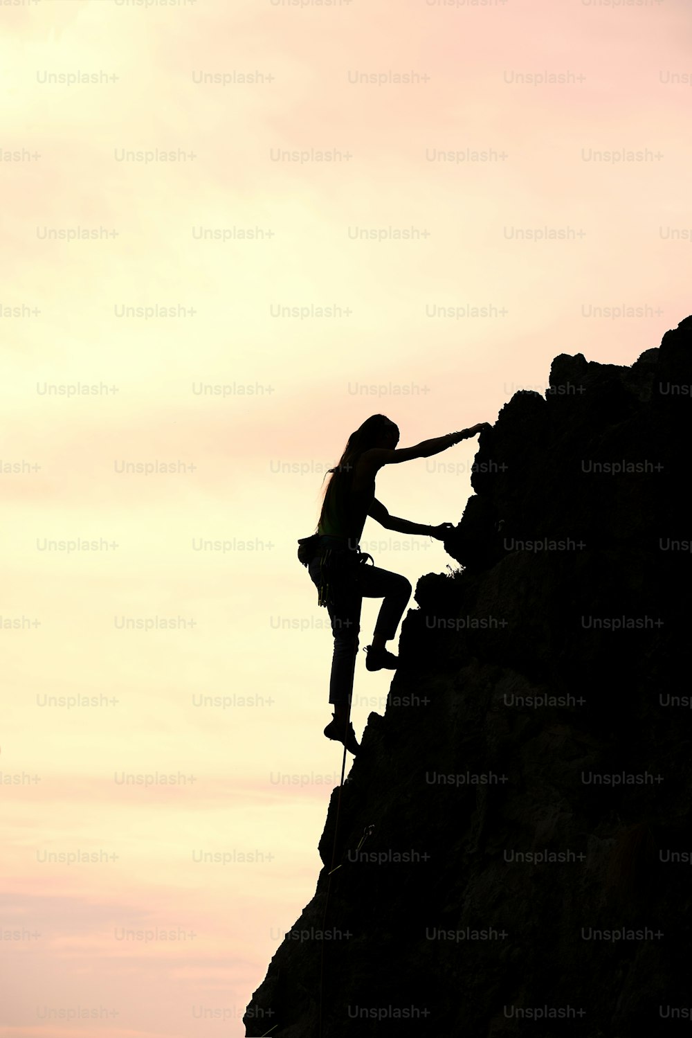 Girl alone conquer the summit during a climb in a fantastic mountain landscape at sunset in summer