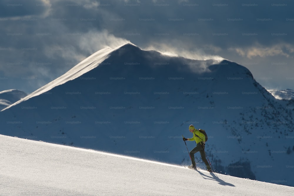 Uomo con racchette da neve in montagna