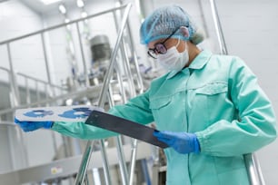 scientist in glasses and mask is looking in tablet, tank on background