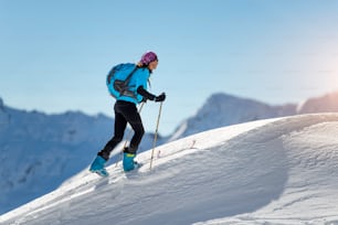 Fille en montée avec des peaux de phoque et ski alpinisme dans les Alpes