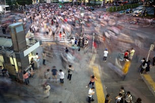 Menschen überqueren die verkehrsreichste Kreuzung der Welt in Shibuya in Tokio, Japan. Eine Langzeitbelichtung wurde verwendet, um dem Bild Bewegung und Unschärfe zu verleihen.