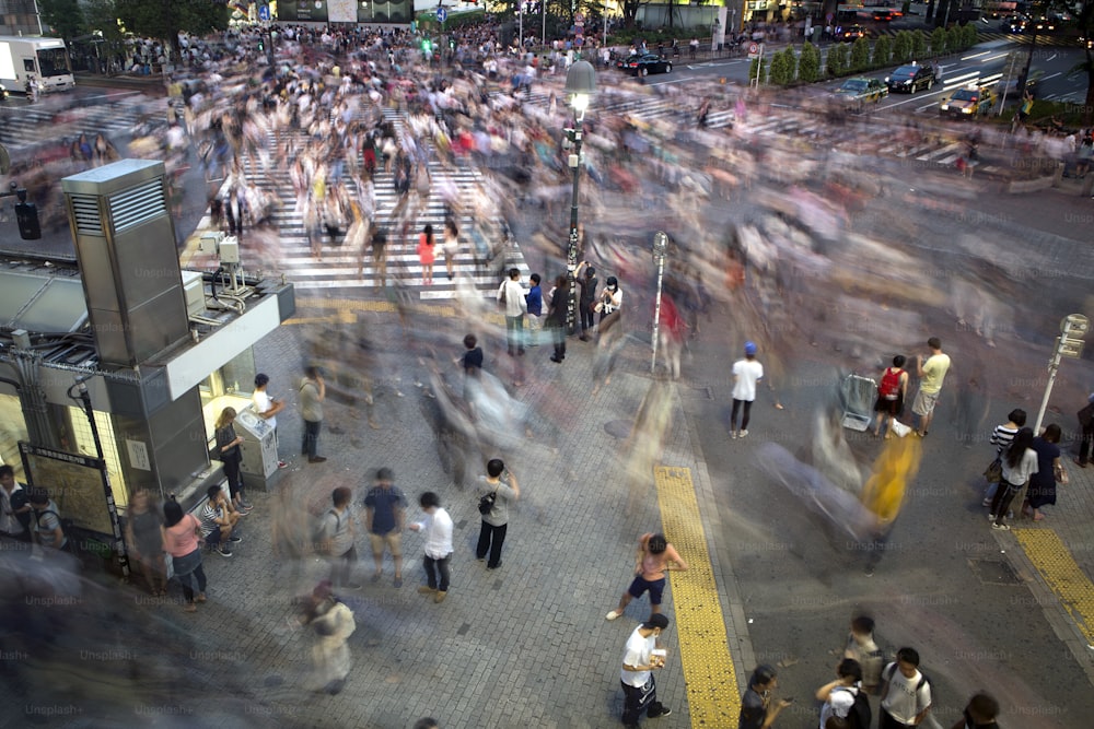 Menschen überqueren die verkehrsreichste Kreuzung der Welt in Shibuya in Tokio, Japan. Eine Langzeitbelichtung wurde verwendet, um dem Bild Bewegung und Unschärfe zu verleihen.