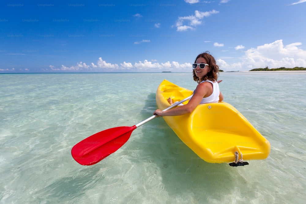 Young caucasian woman kayaking in sea at Maldives