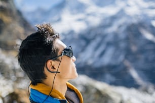 Portrait de profil d’un jeune sherpa portant des lunettes de soleil protectrices dans les montagnes sauvages de l’Himalaya au Népal.