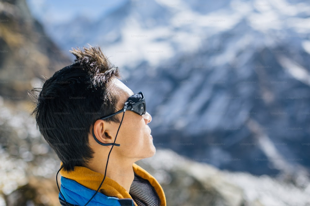 Profile portrait of young Sherpa wearing protective sunglasses in the Himalaya mountain wilderness of Nepal.