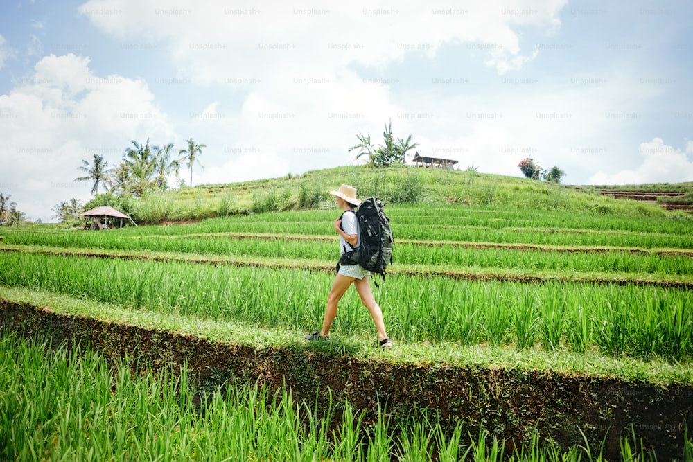 Woman with big backpack traveling at rice fields