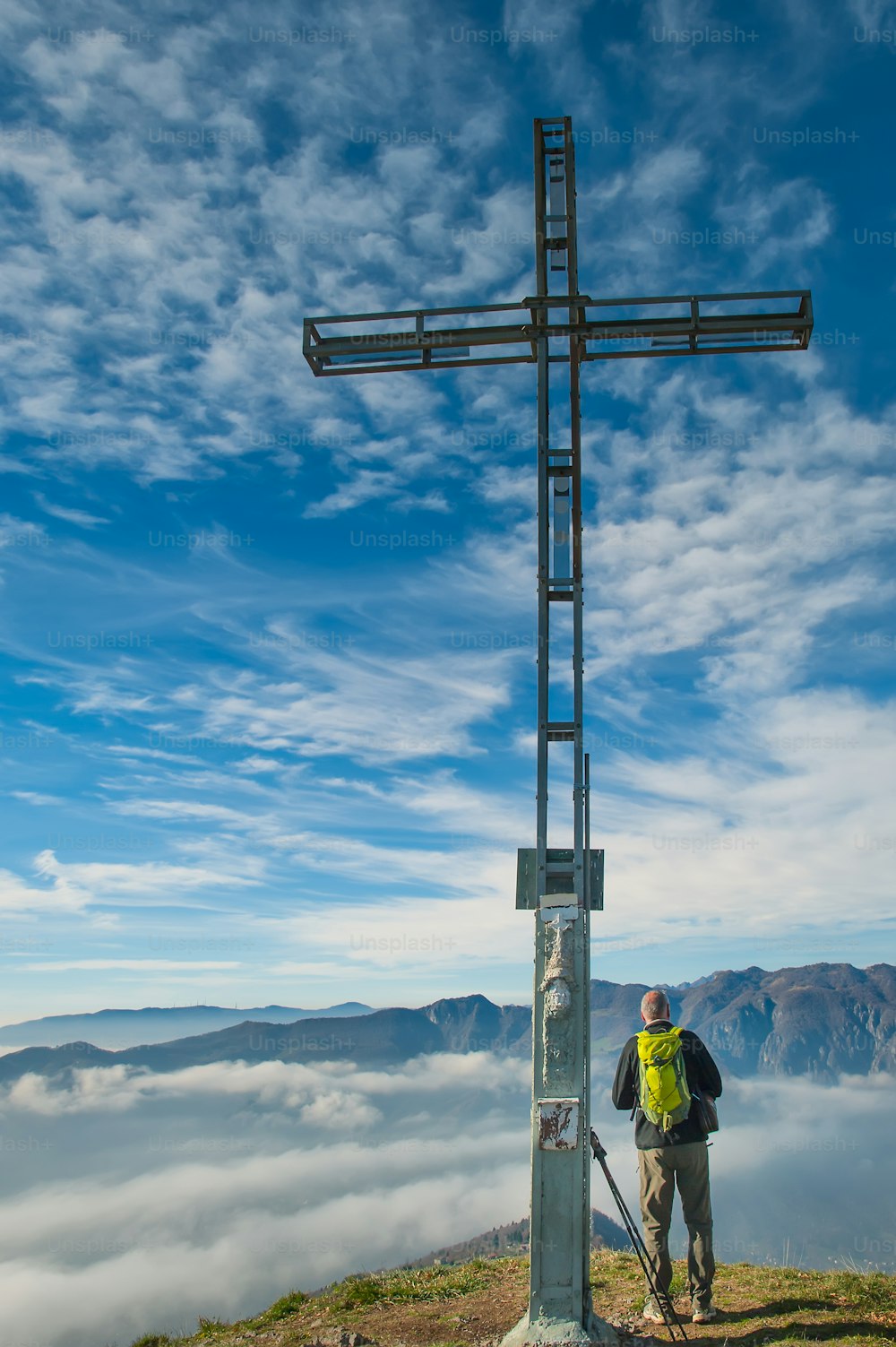 Excursionista masculino en la cima de una montaña con cruz