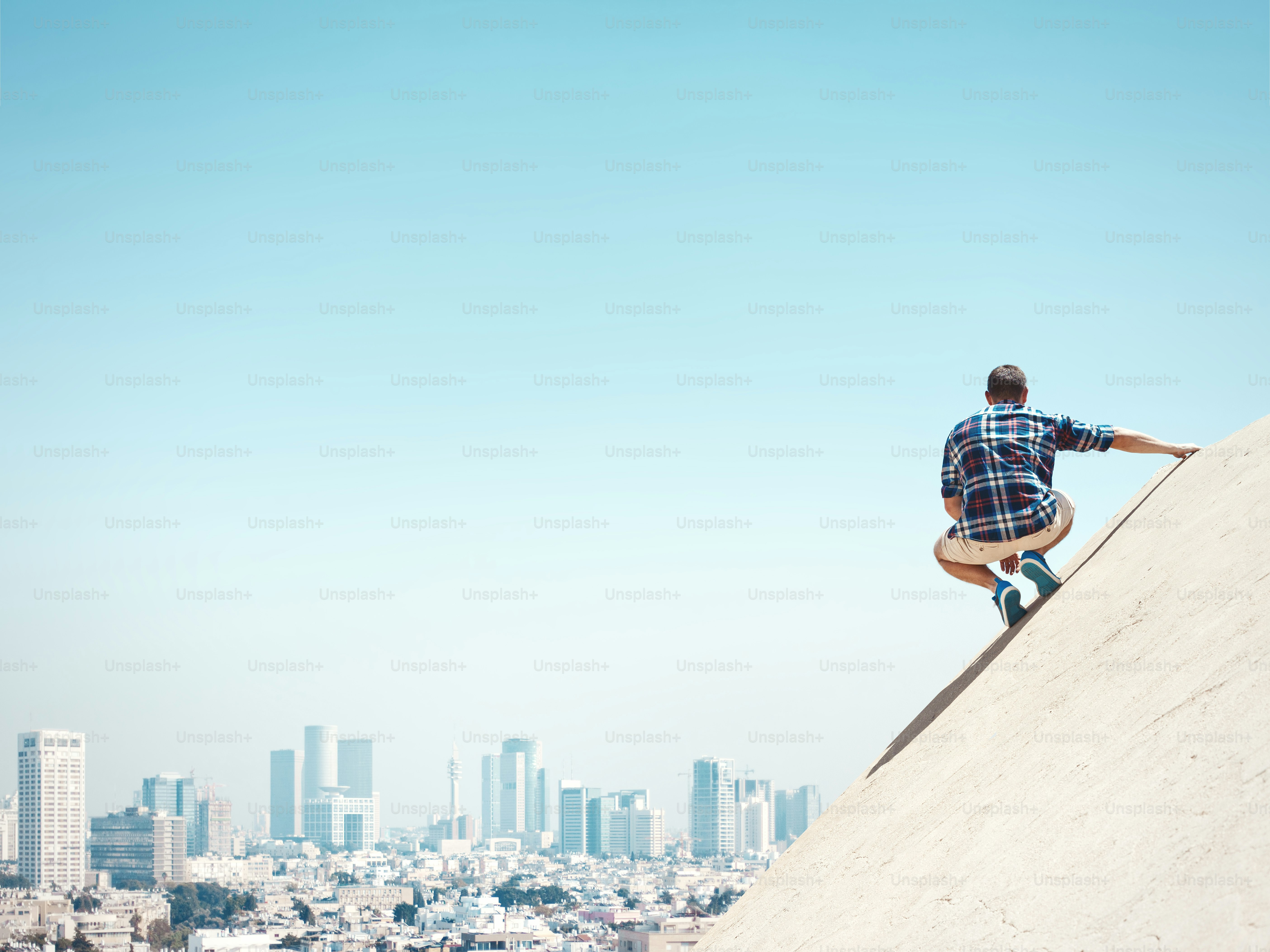 Young and risky man sitting on a peak and looking at the city