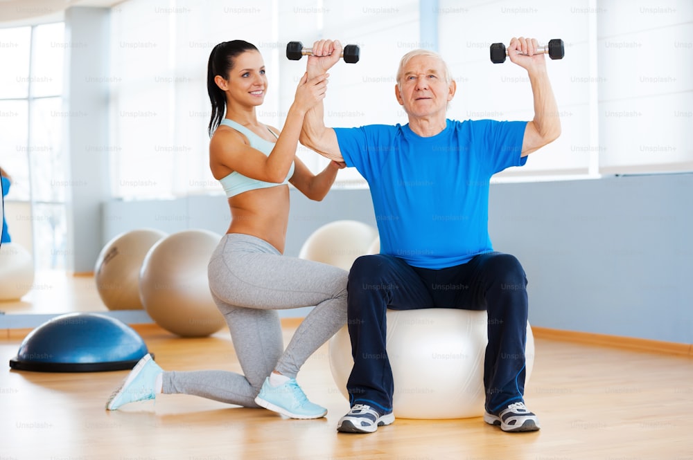 Confident female physical therapist working with senior man in health club