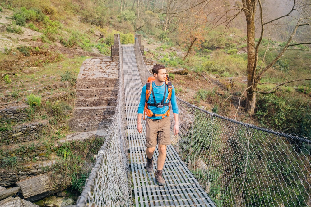 Hiker crossing suspension footbridge in Himalayas.