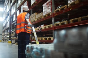 Warehouse forklifter pulling machine while walking along shelves