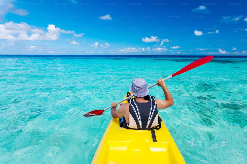 Young caucasian man kayaking in sea at Maldives