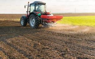 Tractor spreading artificial fertilizers  in field