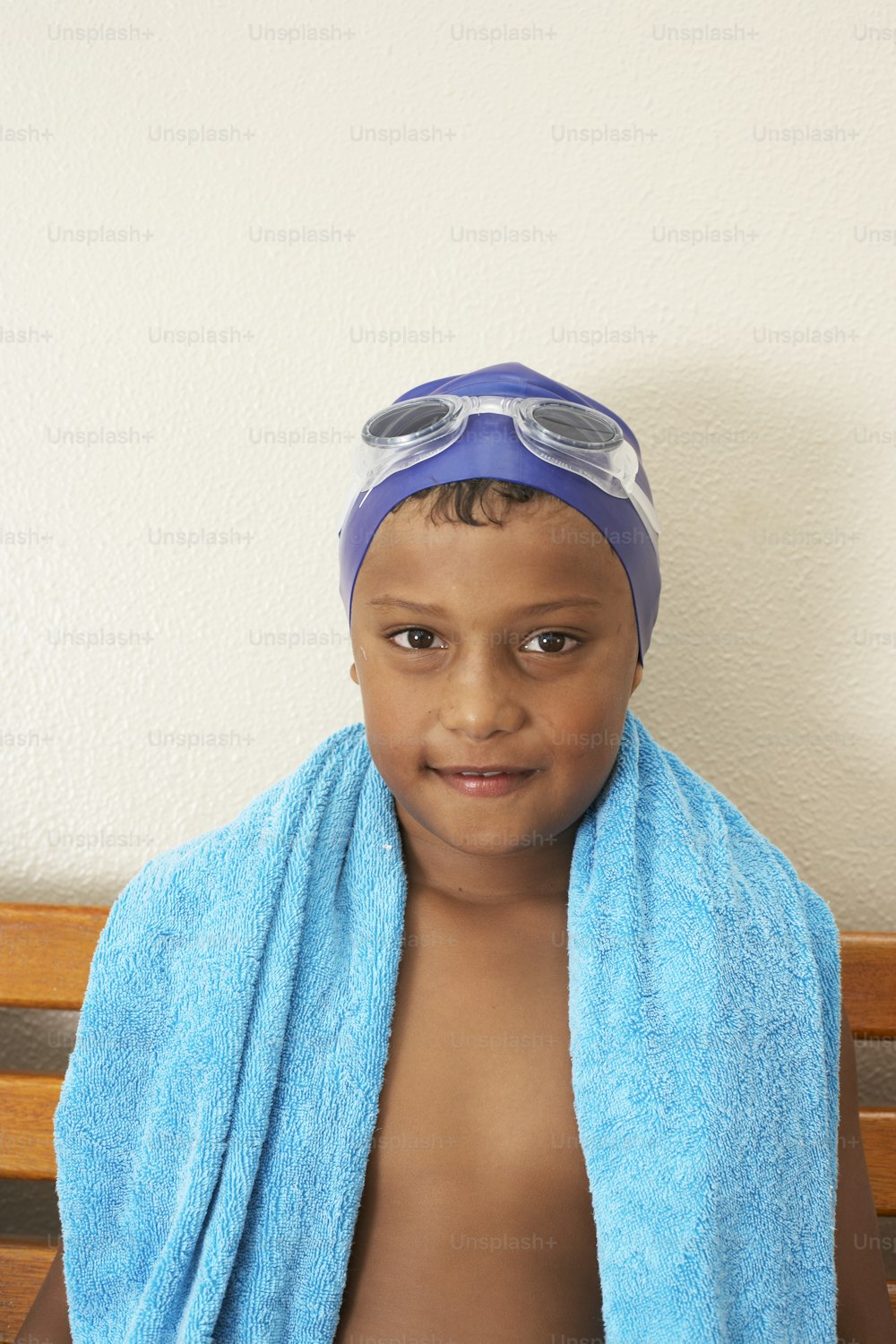 a young boy wearing a blue towel and swimming goggles