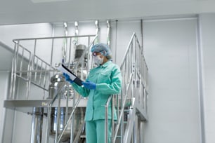 scientist woman in blue suit looking in tablet, standing on stairs