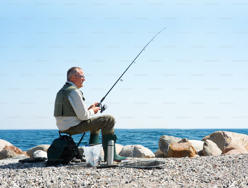 a man sitting on a rock with a fishing pole
