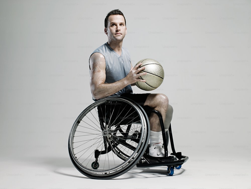 Un hombre en silla de ruedas sosteniendo una pelota de baloncesto