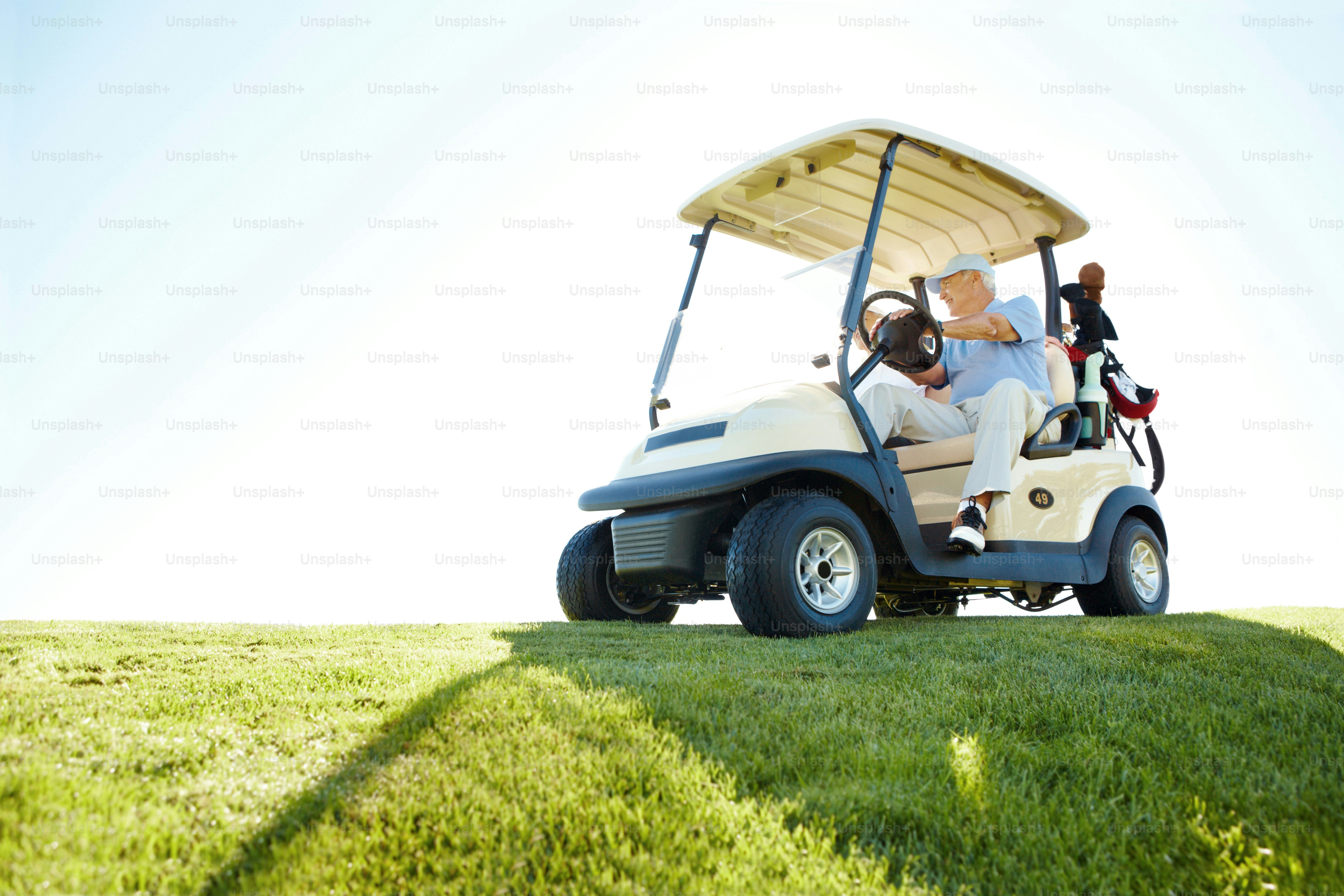 A senior retired couple driving a golf cart on a golf course