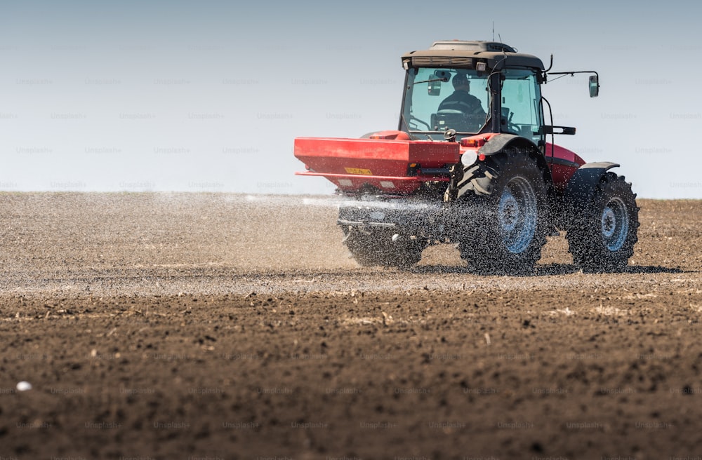 Tractor spreading artificial fertilizers  in field