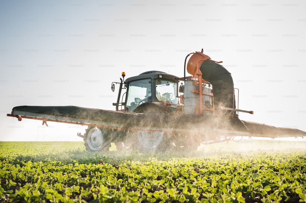 tractor spraying pesticides on soy bean