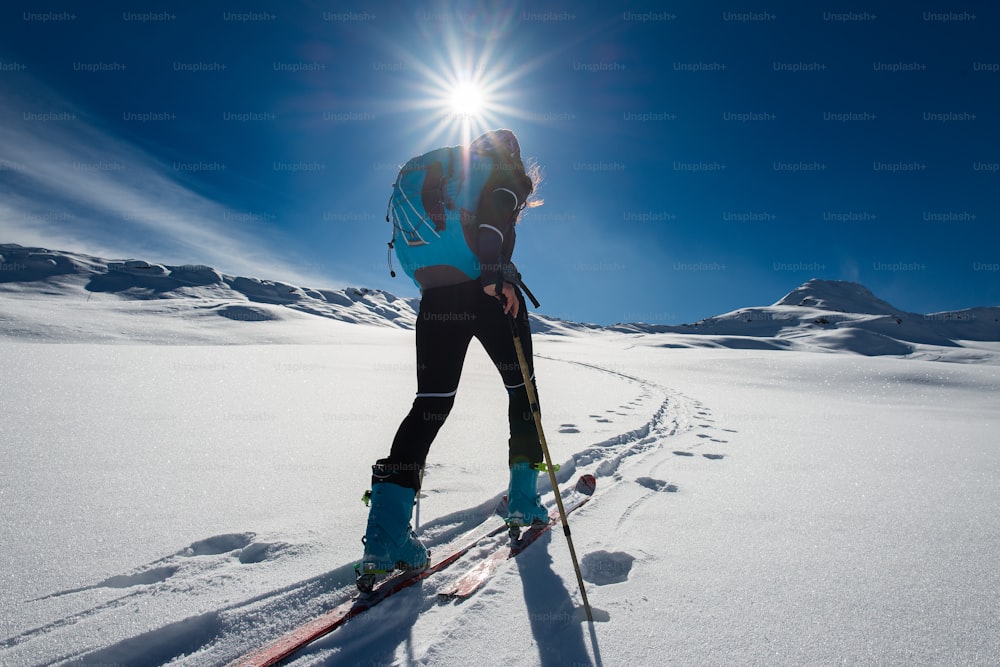 Ascent with ski mountaineering and climbing skins for a single woman in snow landscape