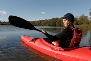 a man sitting in a red kayak on a lake
