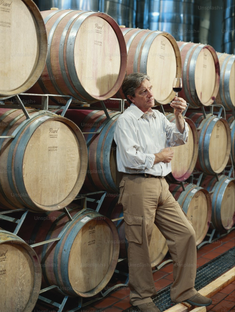 a man standing next to a bunch of wine barrels