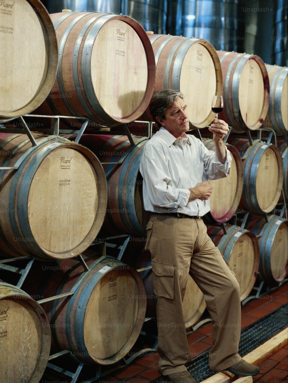 a man standing next to a bunch of wine barrels