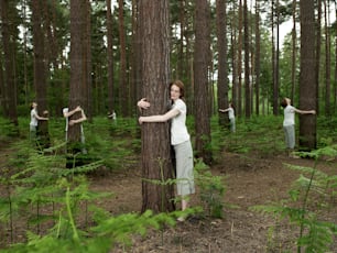 Una mujer parada junto a un árbol en un bosque