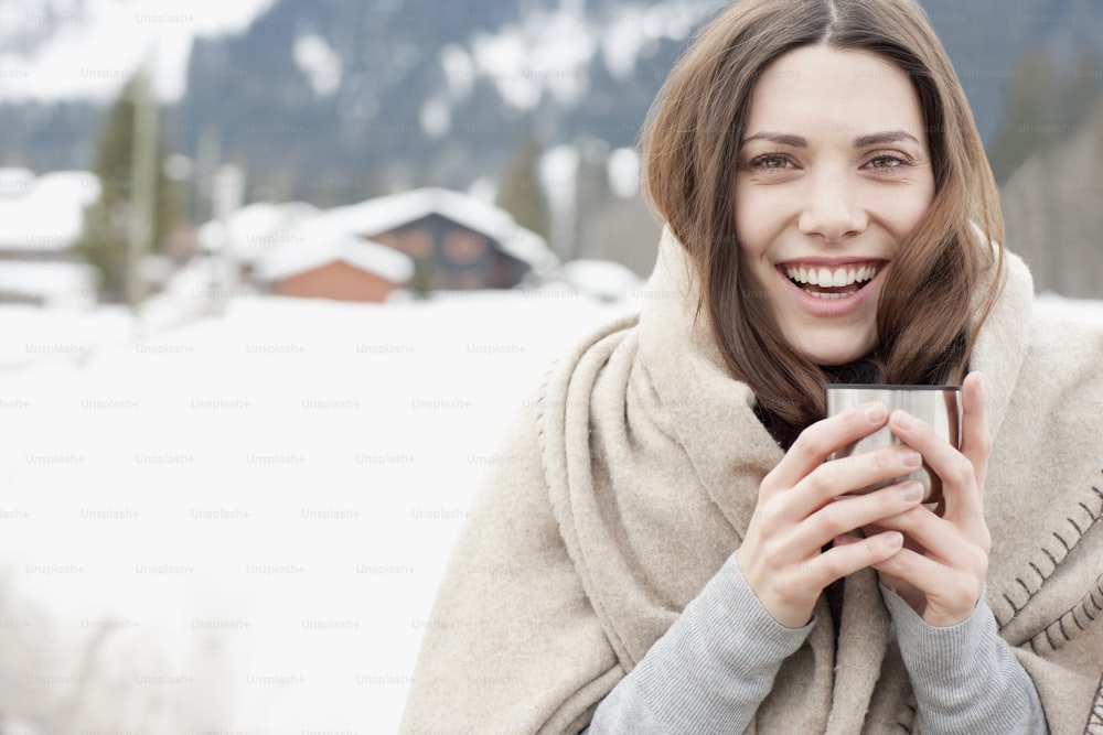 uma mulher segurando uma xícara de café na neve