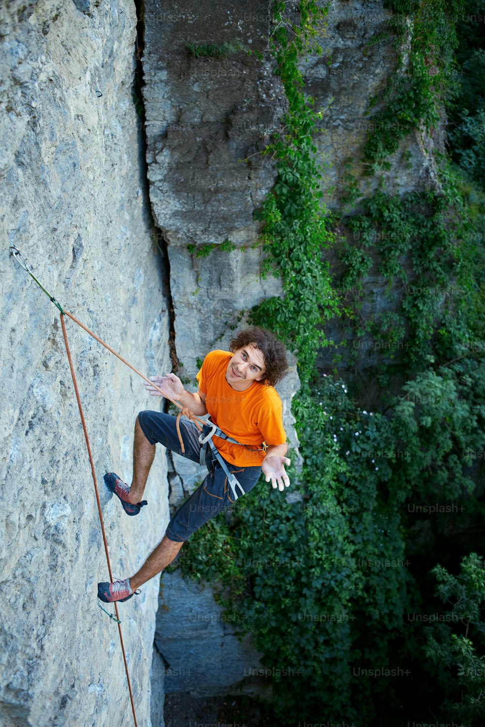 arrampicatore di roccia maschio. arrampicatore su una parete rocciosa. uomo che riposa appeso a una corda