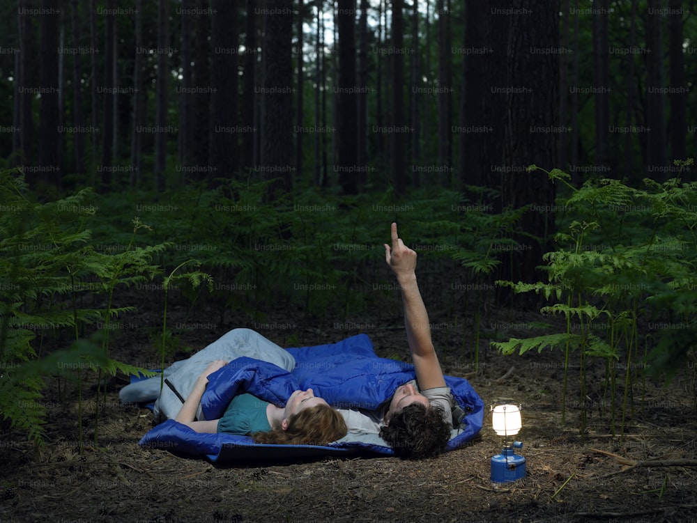 a person laying on a blanket in the woods