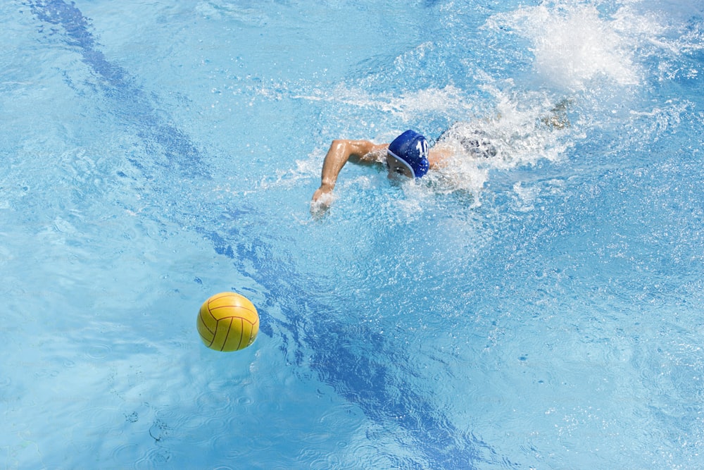 Un homme nageant dans une piscine avec une boule jaune