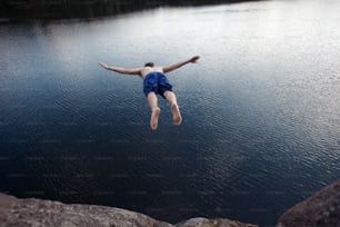 Young man jumping into the water from cliff (man in motion blur)
