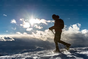 Hombre caminando en la nieve con raquetas de nieve en un paisaje montañoso