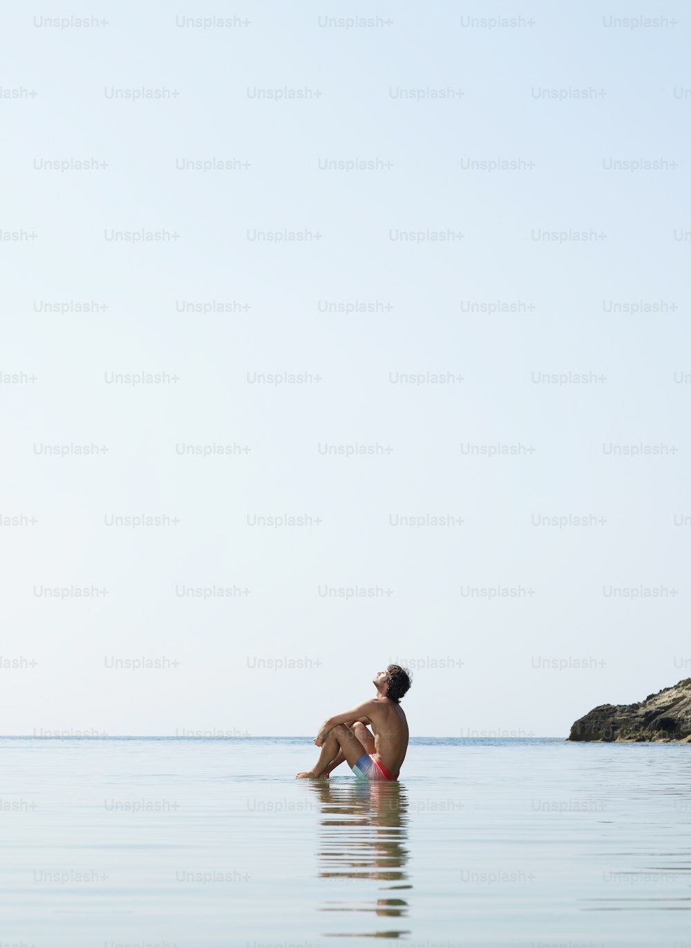 Ein Mann, der auf einem Surfbrett im Meer sitzt