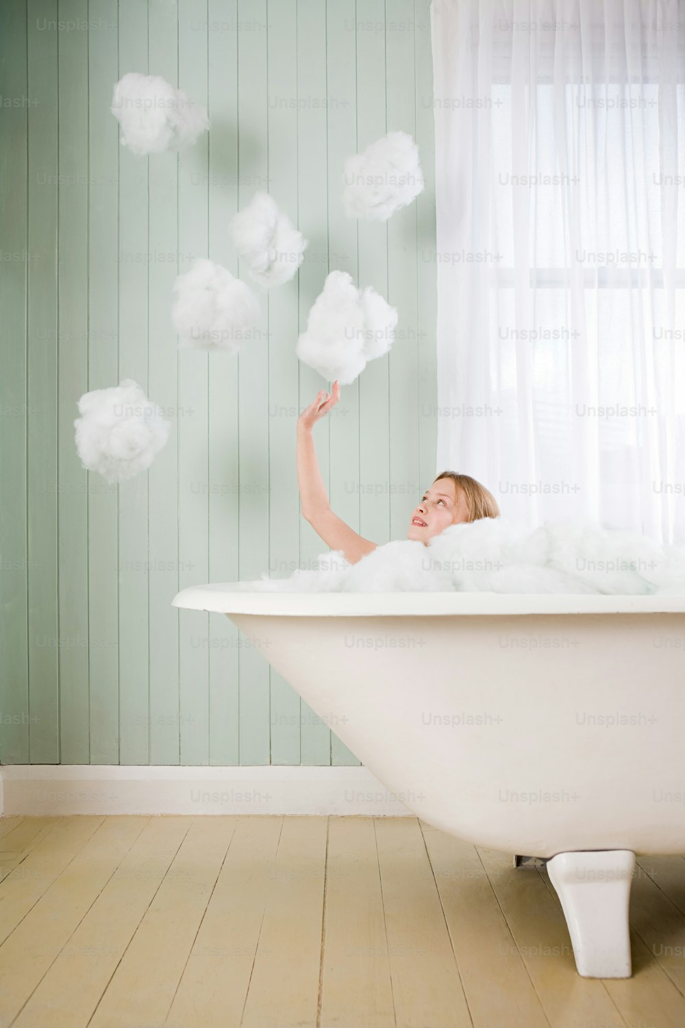 Una mujer acostada en una bañera rodeada de nubes esponjosas