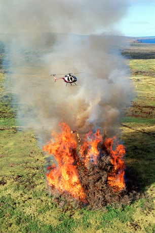 a helicopter flying over a large fire in a field