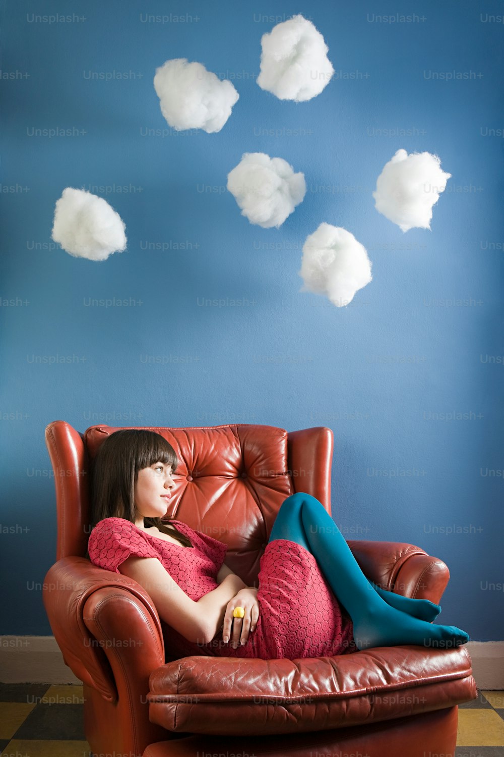 a woman laying on a leather chair in front of a blue wall