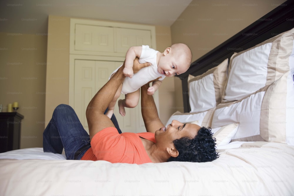 um homem segurando um bebê em seus braços em uma cama