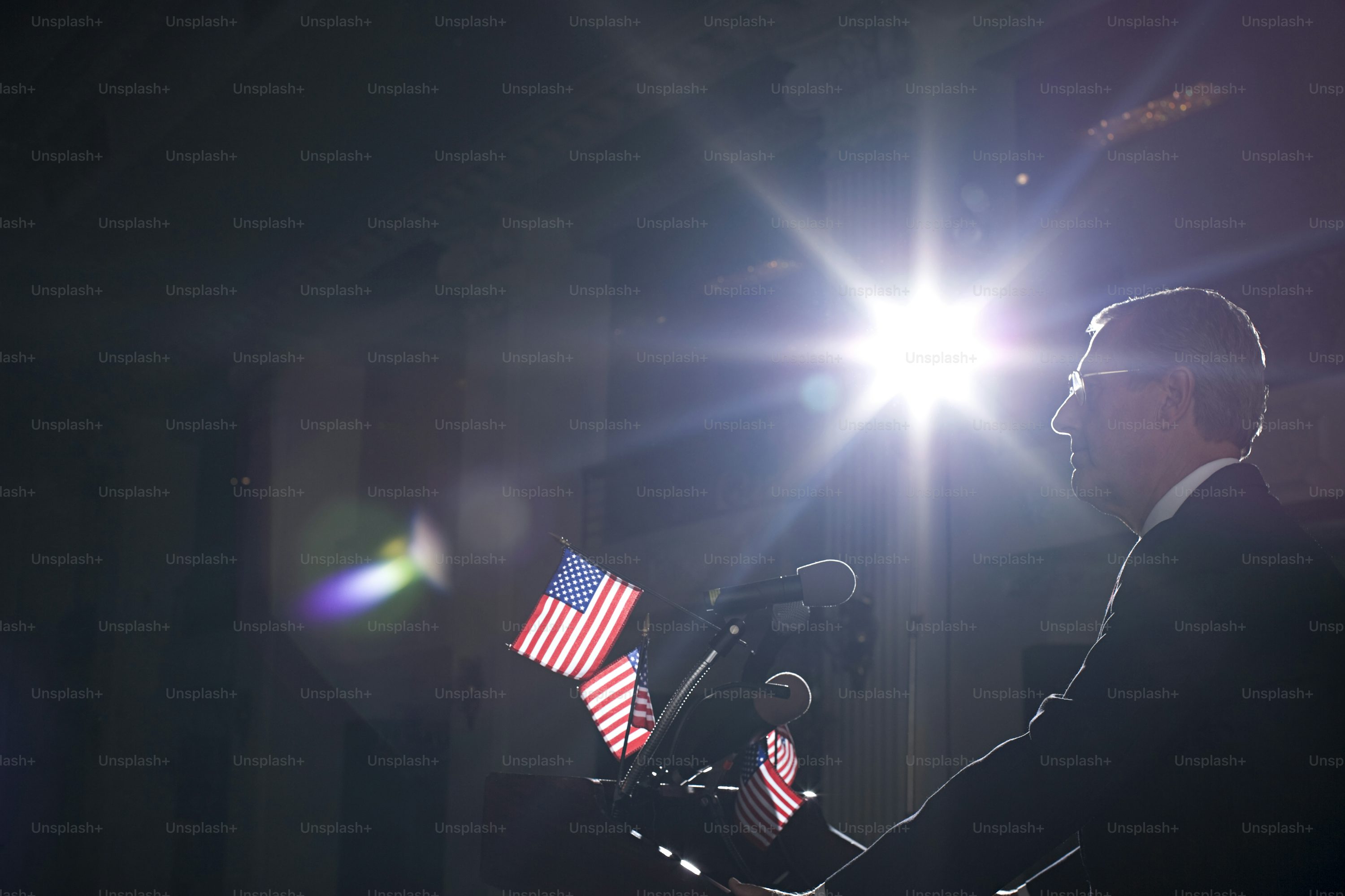 a man standing in front of a microphone holding an american flag
