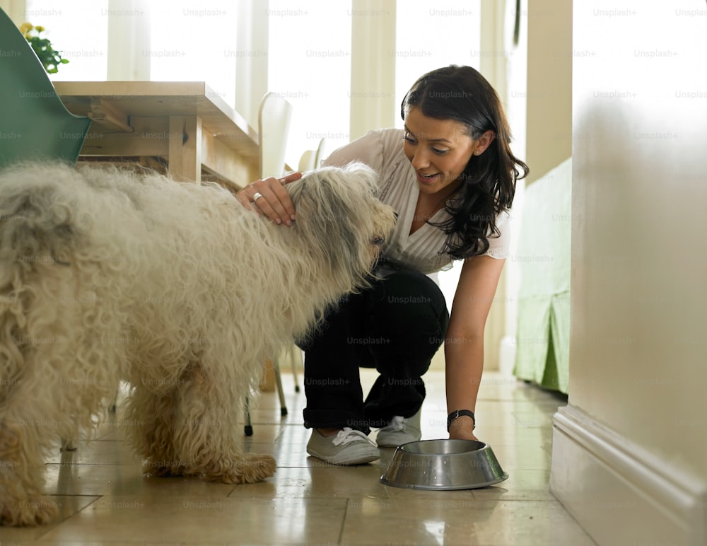a woman is petting a dog on the floor