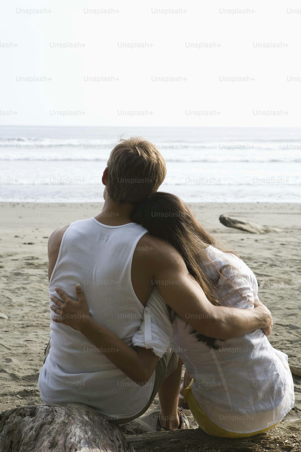 a couple of people sitting on top of a sandy beach