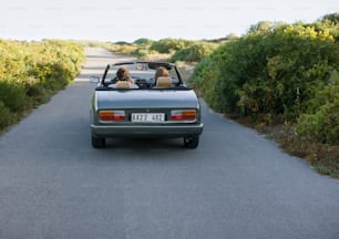 um casal de pessoas em um carro conversível em uma estrada