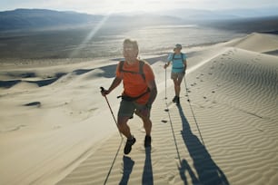 a couple of people walking across a sandy field