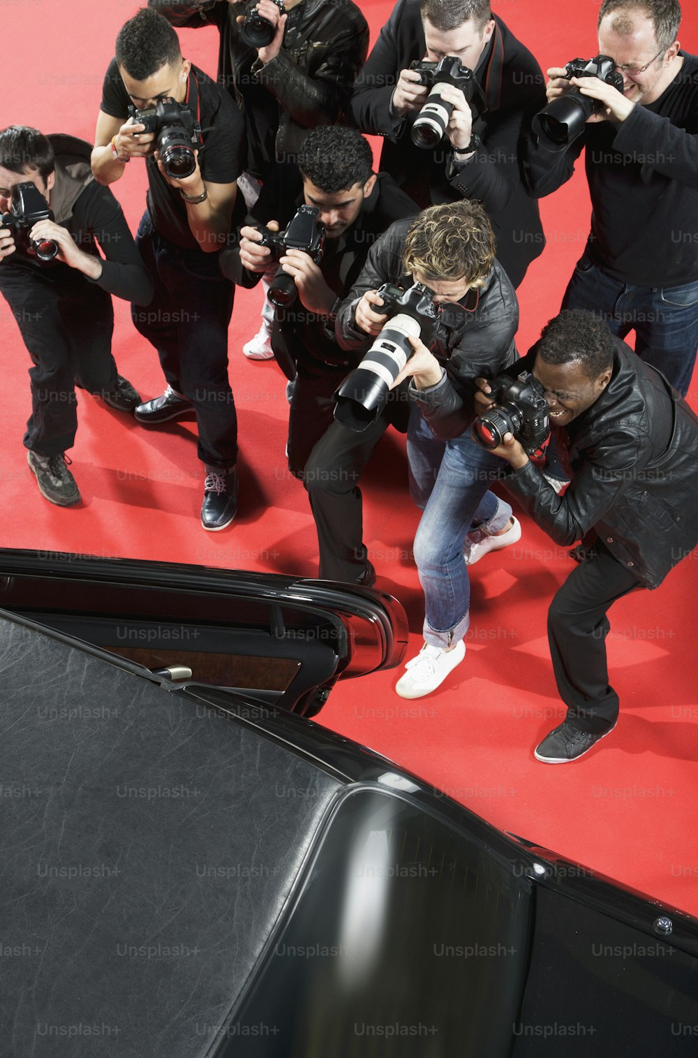 a group of photographers taking pictures of a man on a red carpet