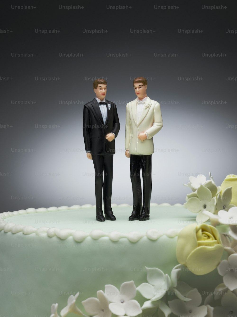 a couple of figurines standing on top of a cake
