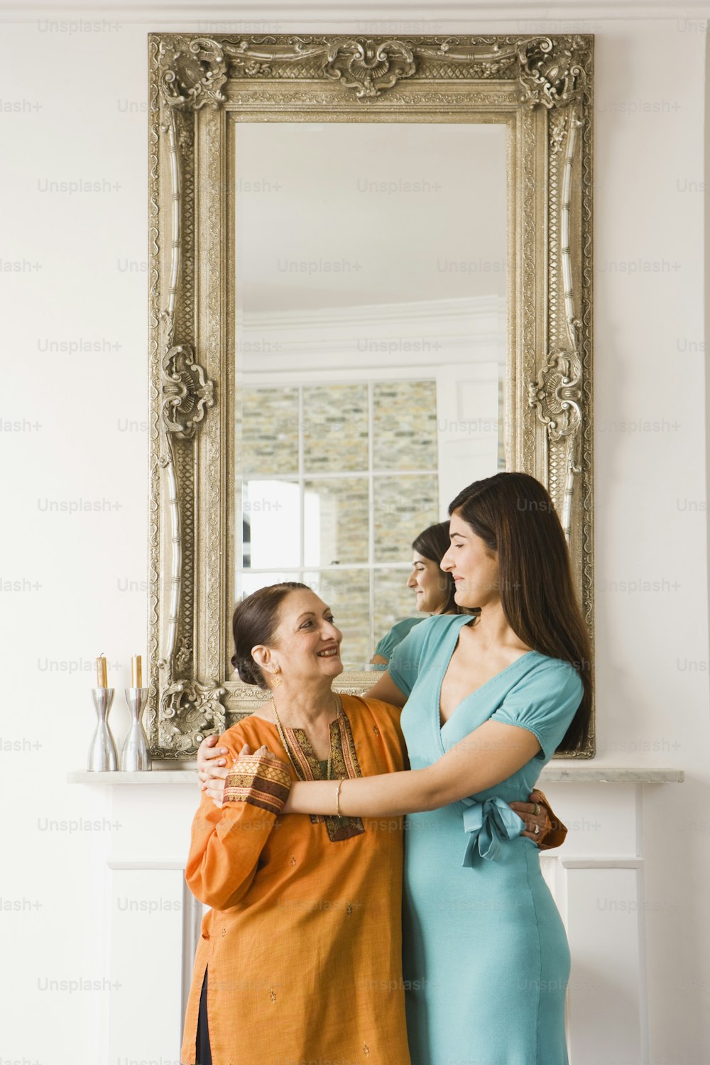 duas mulheres em pé uma ao lado da outra em frente a um espelho
